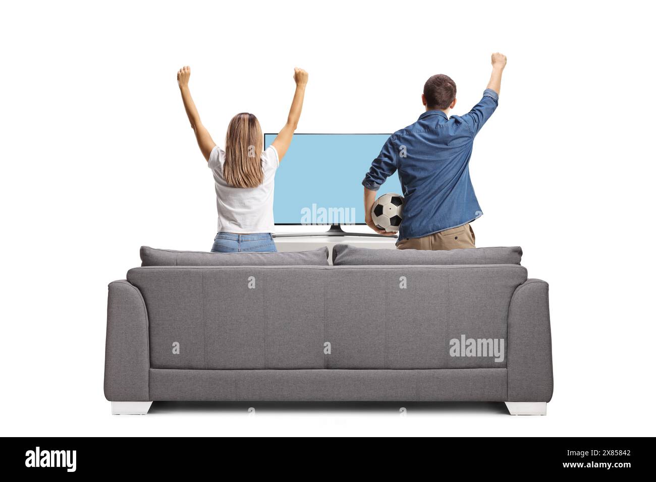 Das aufregende junge Paar sieht ein Fußballspiel im fernsehen an und springt von einem Sofa isoliert auf weißem Hintergrund Stockfoto Das aufregende junge Paar sieht ein Fußballspiel im fernsehen an und springt von einem Sofa isoliert auf weißem Hintergrund Stockfoto