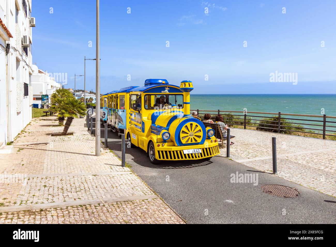 Der kleine Touristenzug fährt entlang der Küstenstraße in Albufeira, Algarve, Portugal Stockfoto