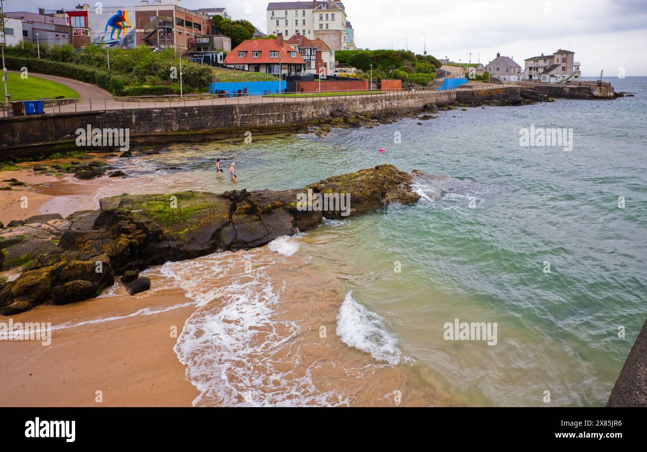 Schwimmer am frühen Morgen am Strand von Arcadia in Portrush, Nordirland Stockfoto
