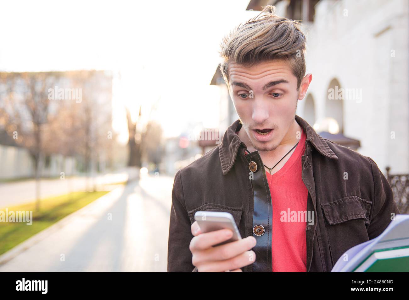 Schockierter Mann, der Nachrichten auf seinem Handy liest, läuft die Straße runter Stockfoto