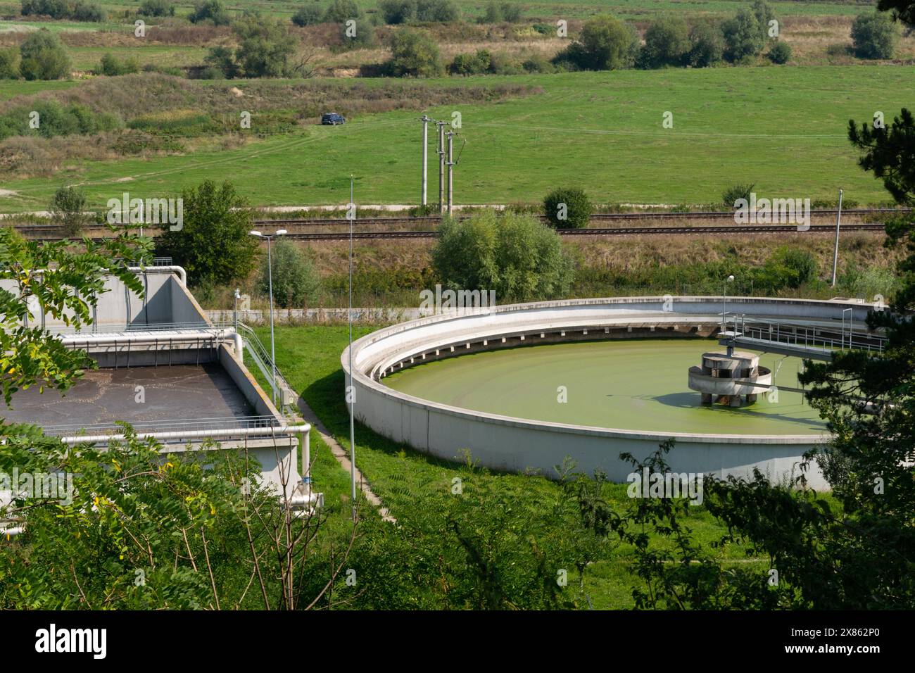 Aus der Vogelperspektive einer Wasseraufbereitungsanlage mit kreisförmigen und rechteckigen Tanks in einer ländlichen Landschaft, umgeben von Grün. Stockfoto