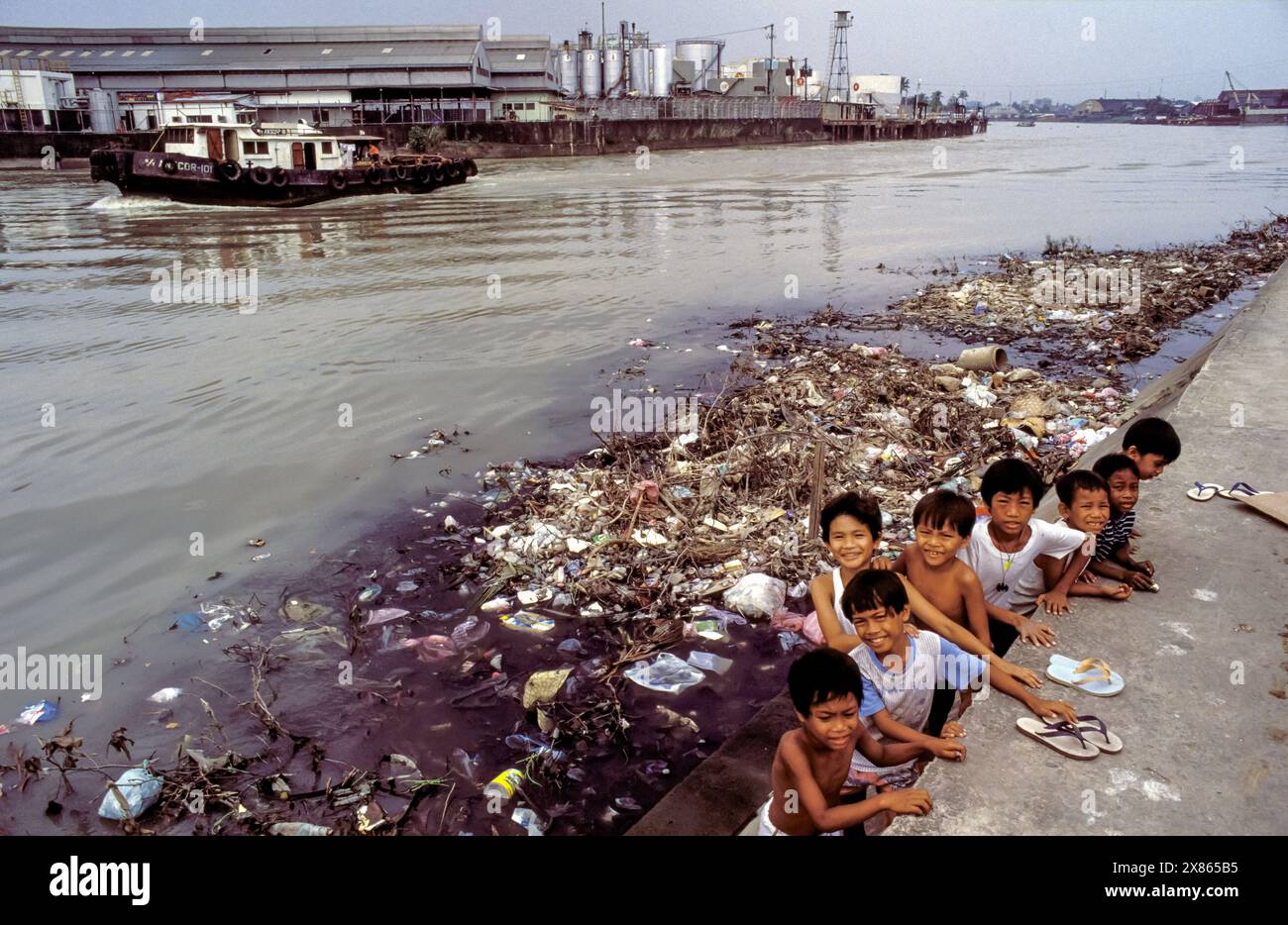 Philippinen, Manila, Kinder hängen auf einer Müllhalde ab, die in einem verschmutzten Fluss schwimmt. Stockfoto
