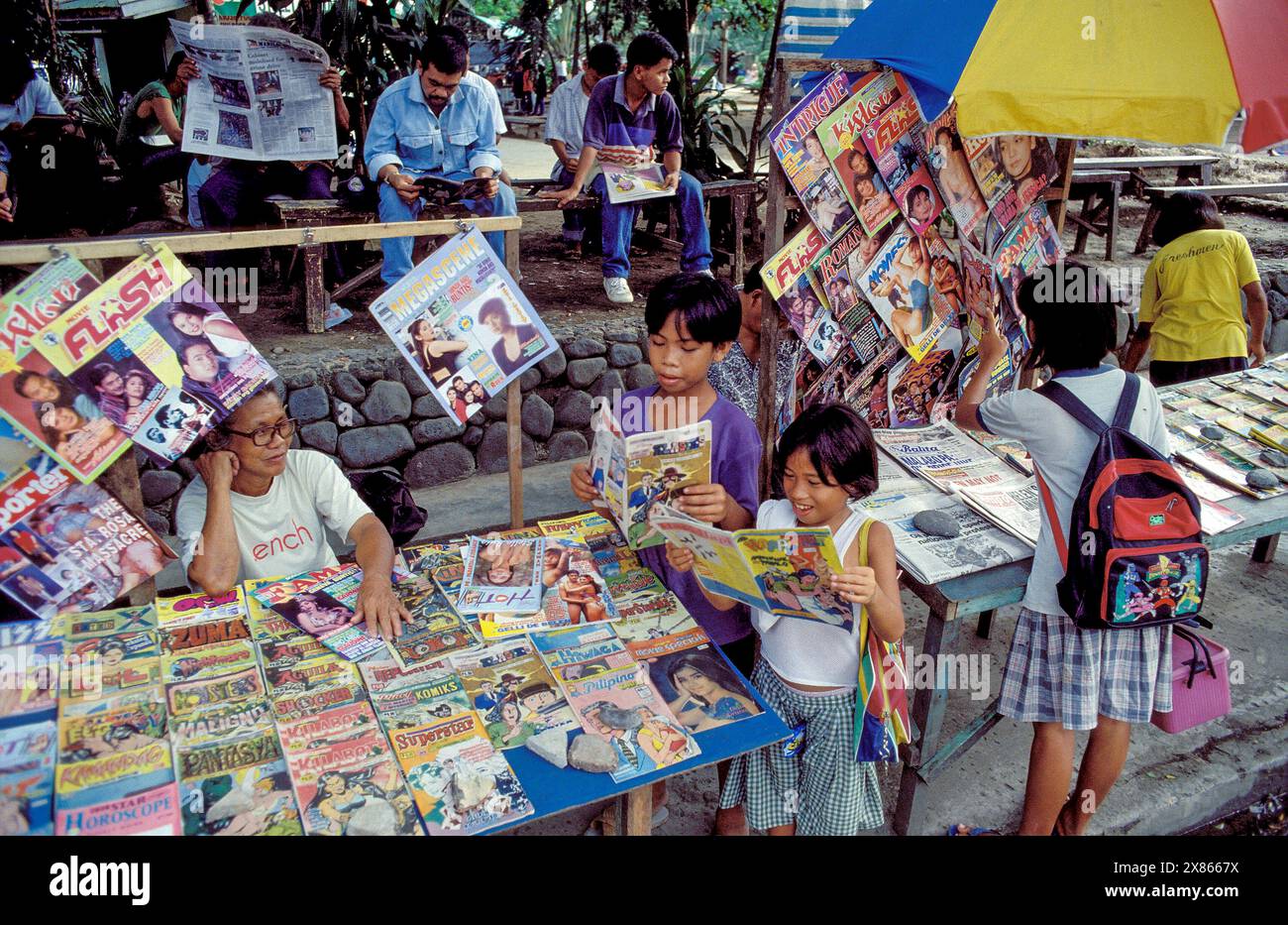 Philippinen, Mindanao. Der Kiosk in Davao verkauft und vermietet Zeitungen, die vor Ort gelesen werden können. Kinder lesen Comics. Stockfoto