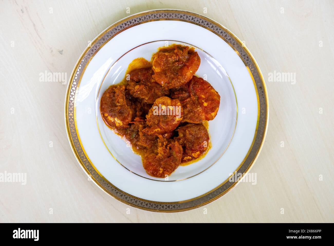 Köstliches bengalisches Essen Chingri Bhuna serviert auf einem weißen Teller. Chingri Vuna oder Garnelenfischcurry ist ein Gericht nach Bangladeshi-Art mit scharfer Soße. Draufsicht. Stockfoto