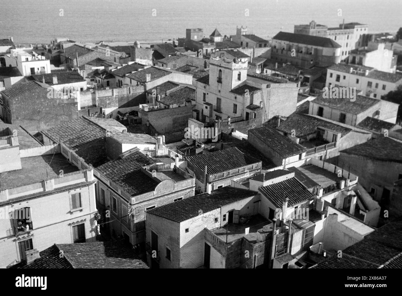 Blick vom Glockenturm auf die umliegende Ortschaft von Calella an der Costa del Maresme, im Hintergrund ist die Oberfläche des Mittelmeeres erkennbar, Katalonien 1957. Blick vom Glockenturm des umliegenden Dorfes Calella an der Costa del Maresme, mit der Oberfläche des Mittelmeers im Hintergrund, Katalonien 1957. Stockfoto