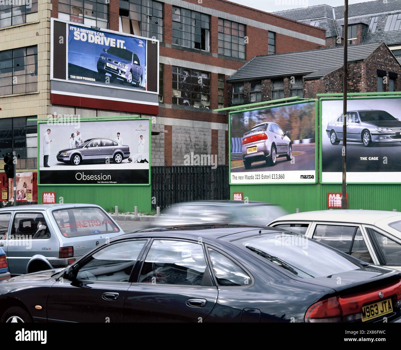 Autokultur: Autos, die Werbung für neue Autos passieren, Great Ancoats Street, Manchester. Stockfoto