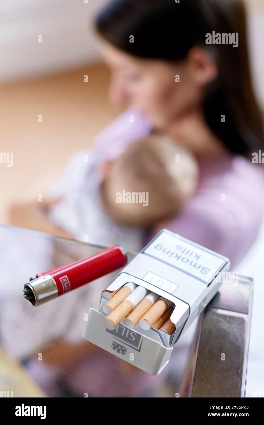 Frau raucht neben neugeborenem Baby Stockfoto