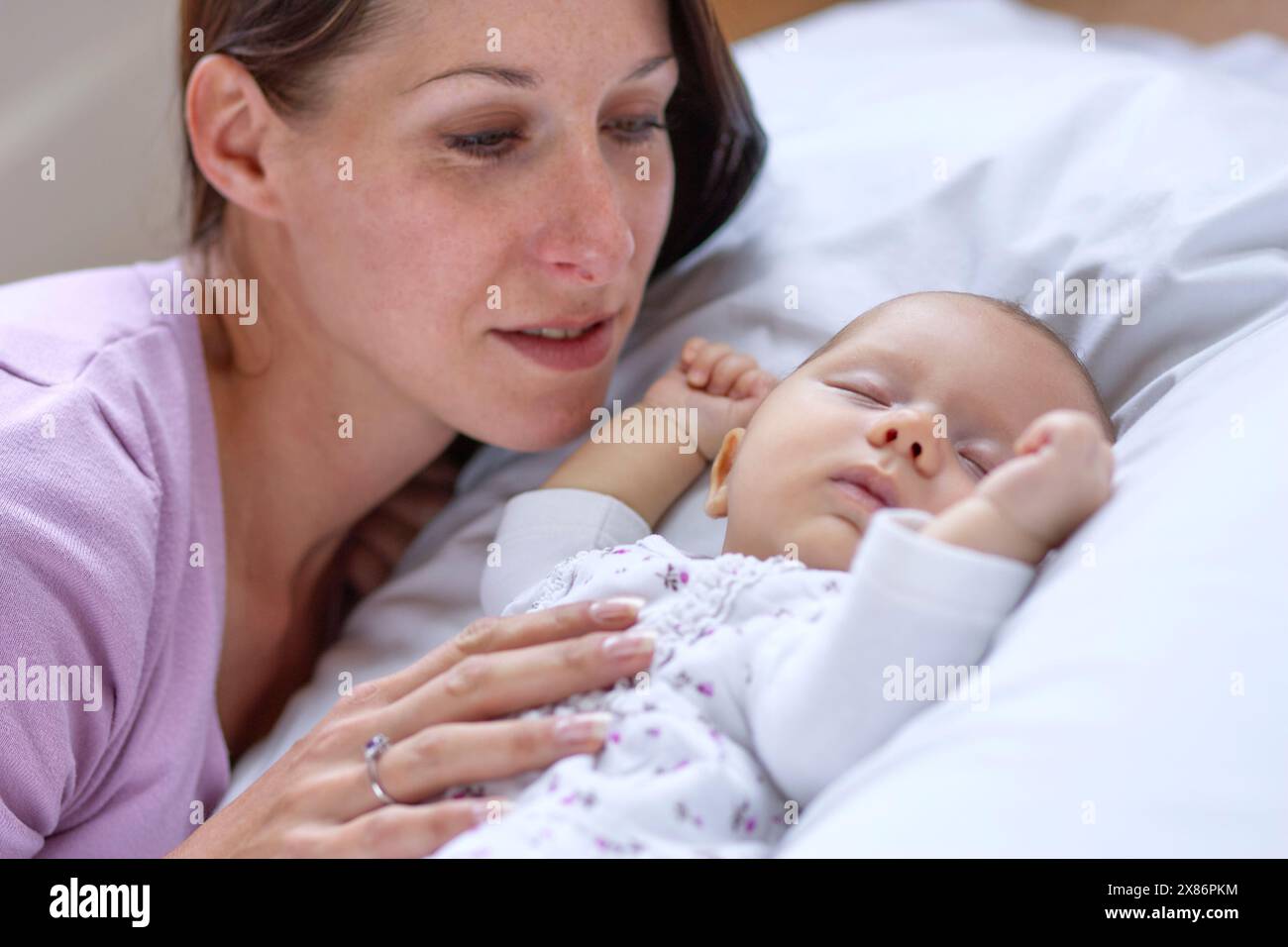 Baby schläft neben Mutter Stockfoto