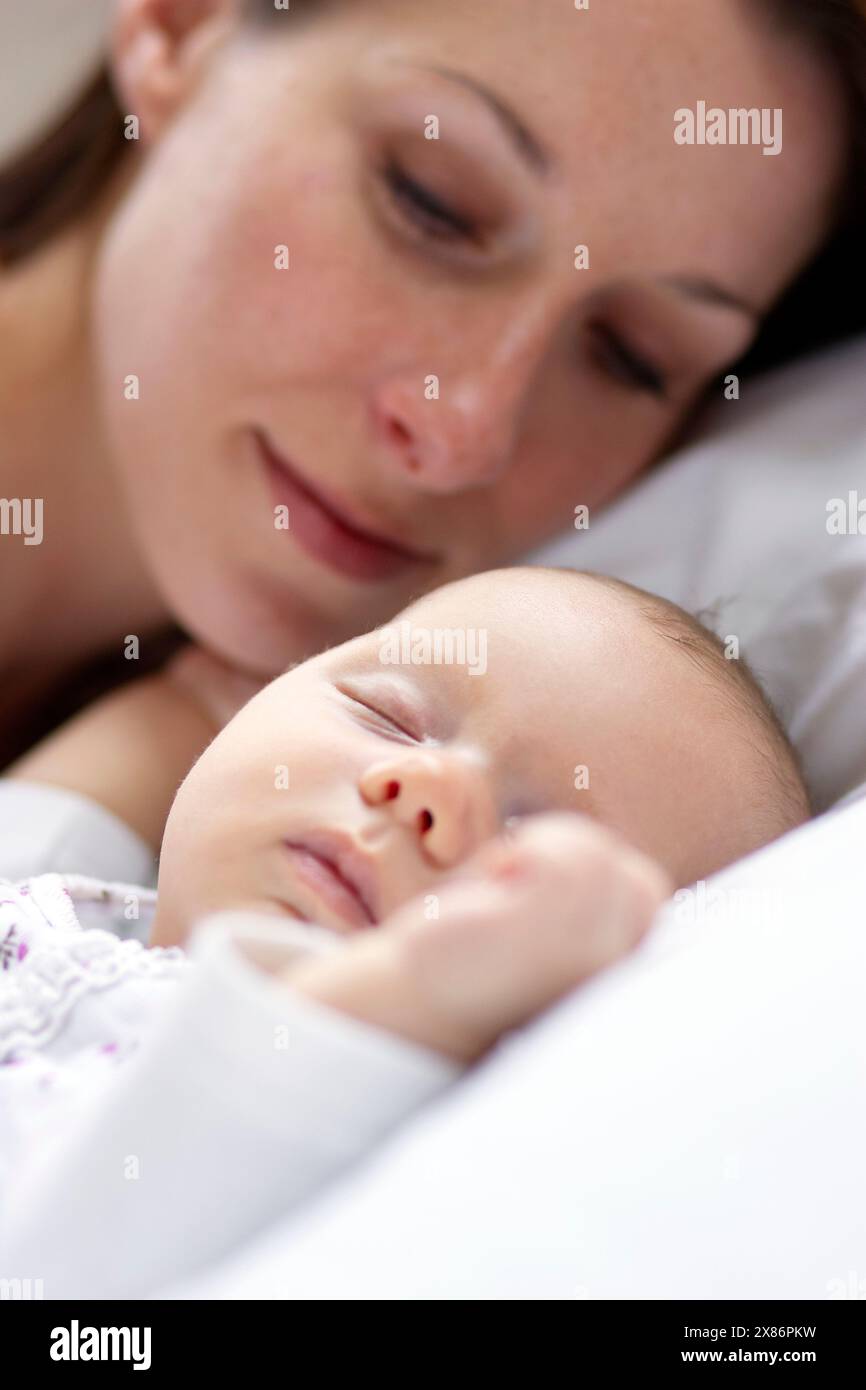 Baby schläft neben Mutter Stockfoto