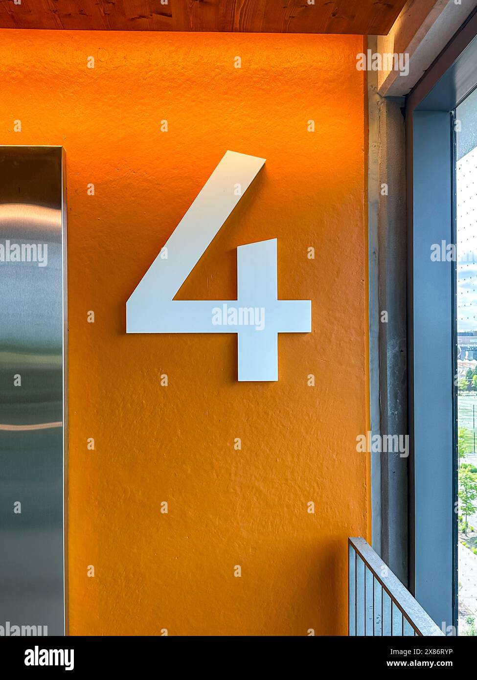 Etage 4 in einer Parkrampe, Garage, Parkplatz mit einer großen weißen Nummer auf orangem Hintergrund. Stockfoto