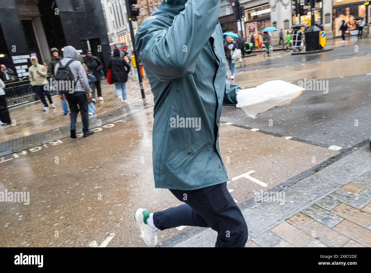 Ein Mann mit Mittagessen in der Hand läuft über eine Londoner Straße, Großbritannien Stockfoto