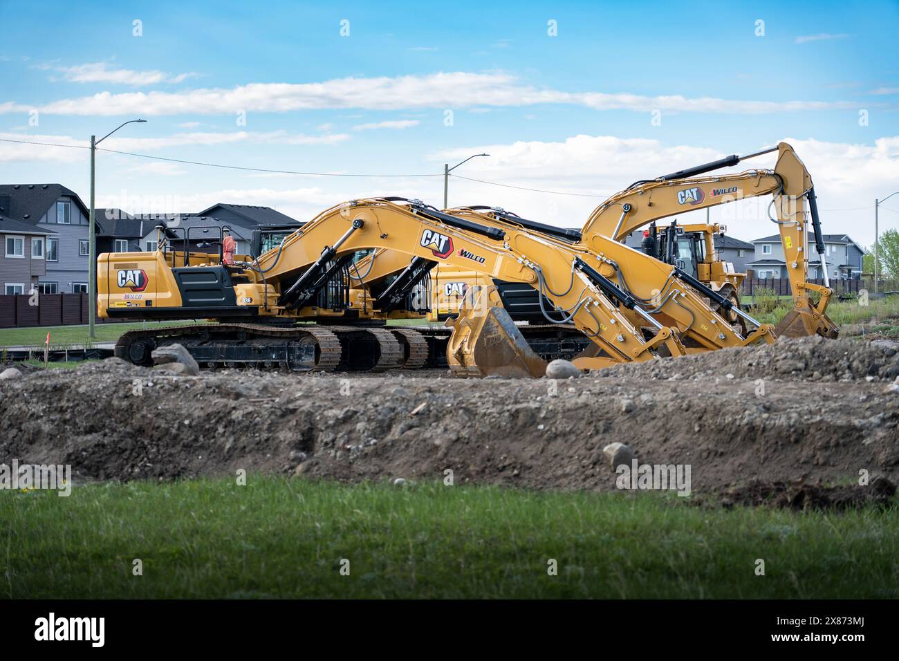 Airdrie Alberta Canada, 18. Mai 2024: Eine Reihe von Baggern parkte bereit für den Bau einer neuen Wohnsiedlung. Stockfoto