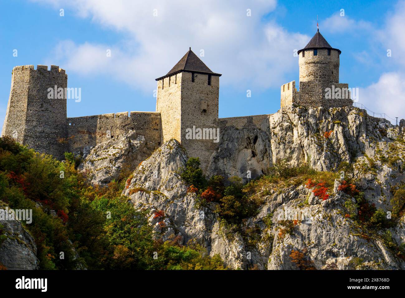 Atemberaubende mittelalterliche Festung hoch oben auf felsigen Klippen mit klarem blauem Himmel und lebhaftem Herbstlaub, die die ruhige Kulisse des Donauflusses bereichern Stockfoto