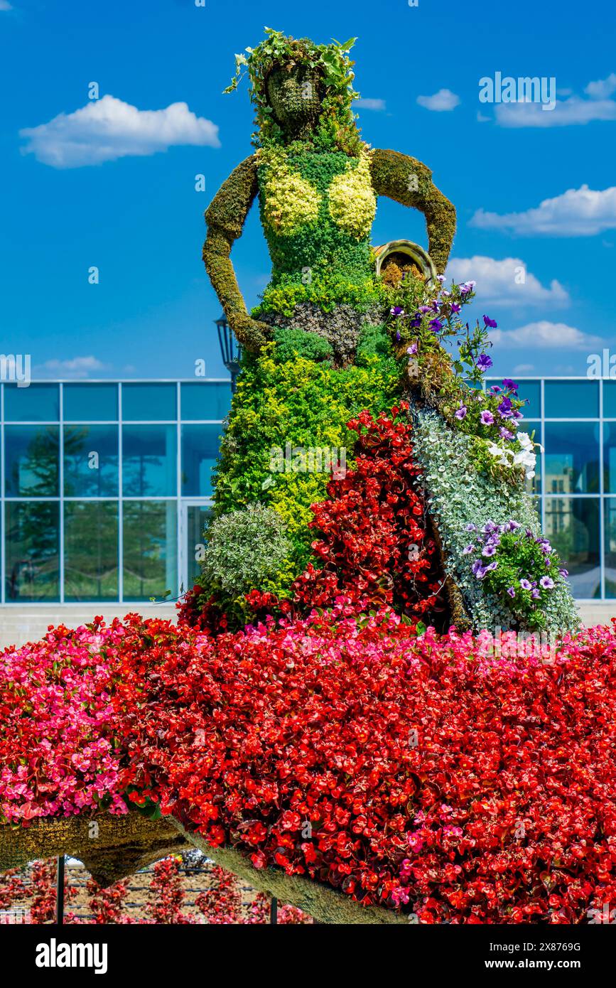Wunderschön gefertigte Blumenskulptur umgeben von üppigem Grün und bunten Blumenbeeten in Kladovo, Serbien, unter einem strahlenden Sommerhimmel Stockfoto