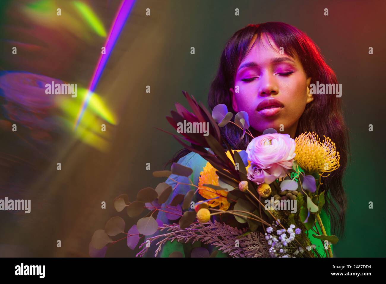 Frau mit geschlossenen Augen inmitten bunter Blumen und Neonlichtern Stockfoto