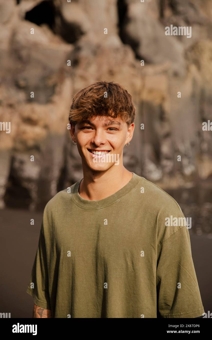 Lächelnder junger Mann in T-Shirt am Strand Stockfoto