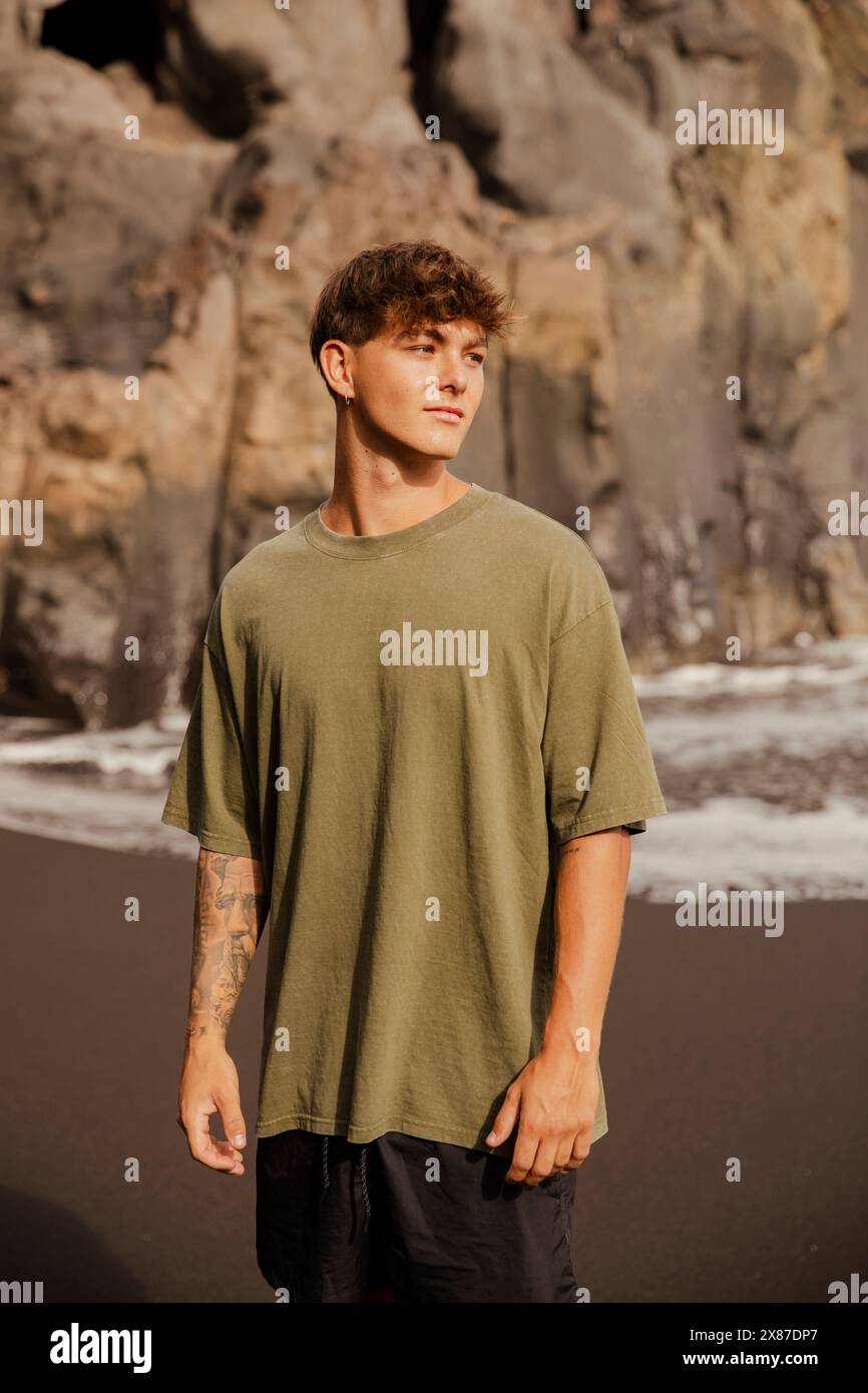 Schöner Mann in T-Shirt, der am Strand steht Stockfoto