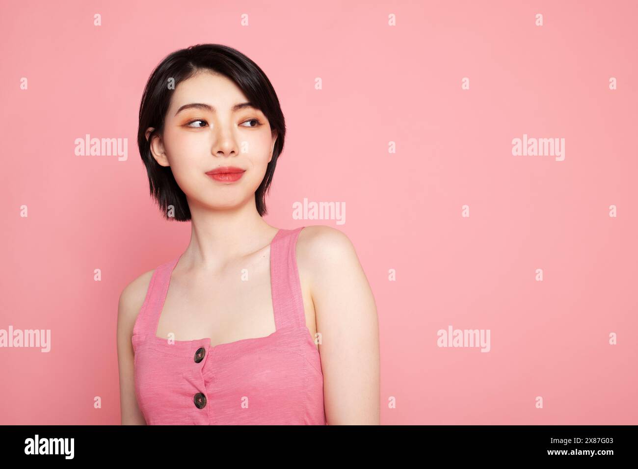 Lächelnde Frau mit kurzen Haaren vor rosa Hintergrund Stockfoto