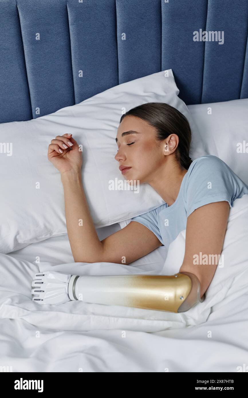 Junge Frau mit bionischer Hand, die im Bett liegt Stockfoto