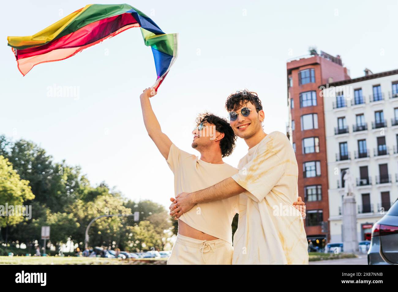 Sorgloses Schwulenpaar mit Regenbogenfahne bei der Gay Pride Parade Stockfoto