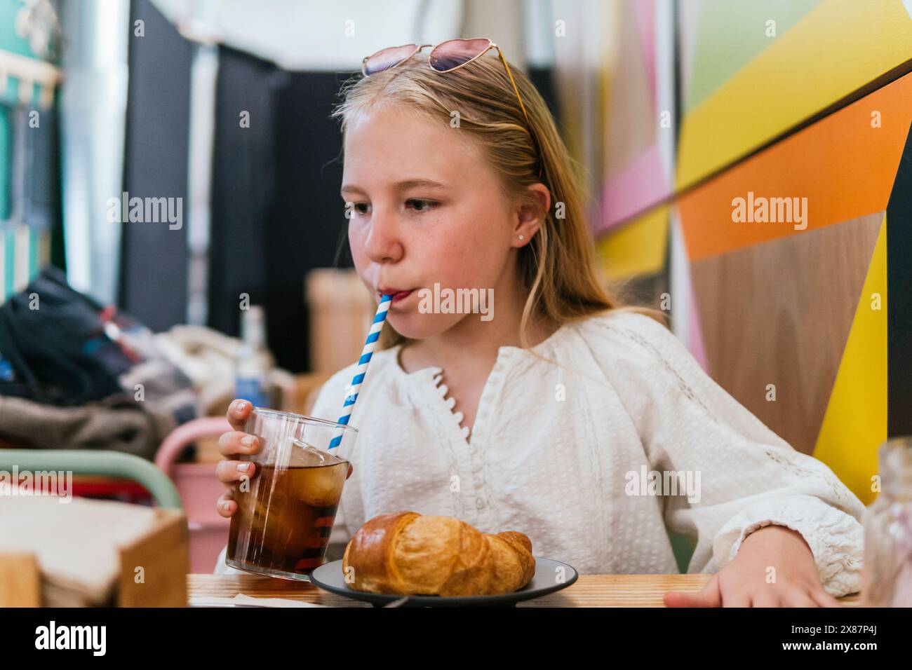 Blondes Mädchen schlürft Cola im Restaurant Stockfoto