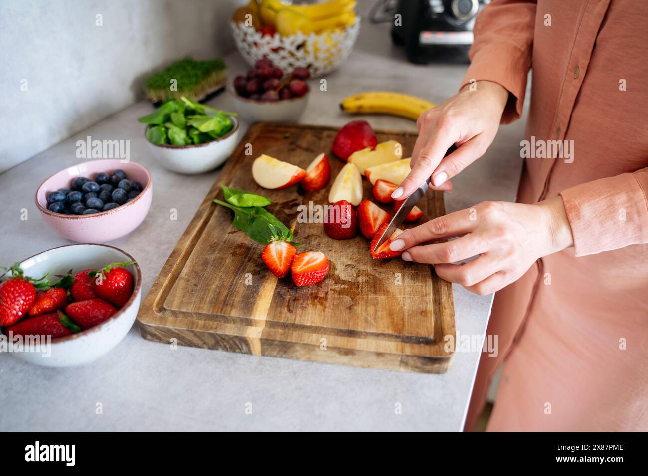 Frau schneidet Erdbeeren auf der Küchenzeile zu Hause Stockfoto