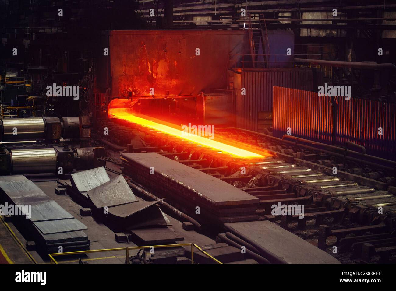 Walzmetallfabrik. Heiße Eisenplatte, die sich auf dem Förderband des Metallwalzwerks bewegt. Stockfoto