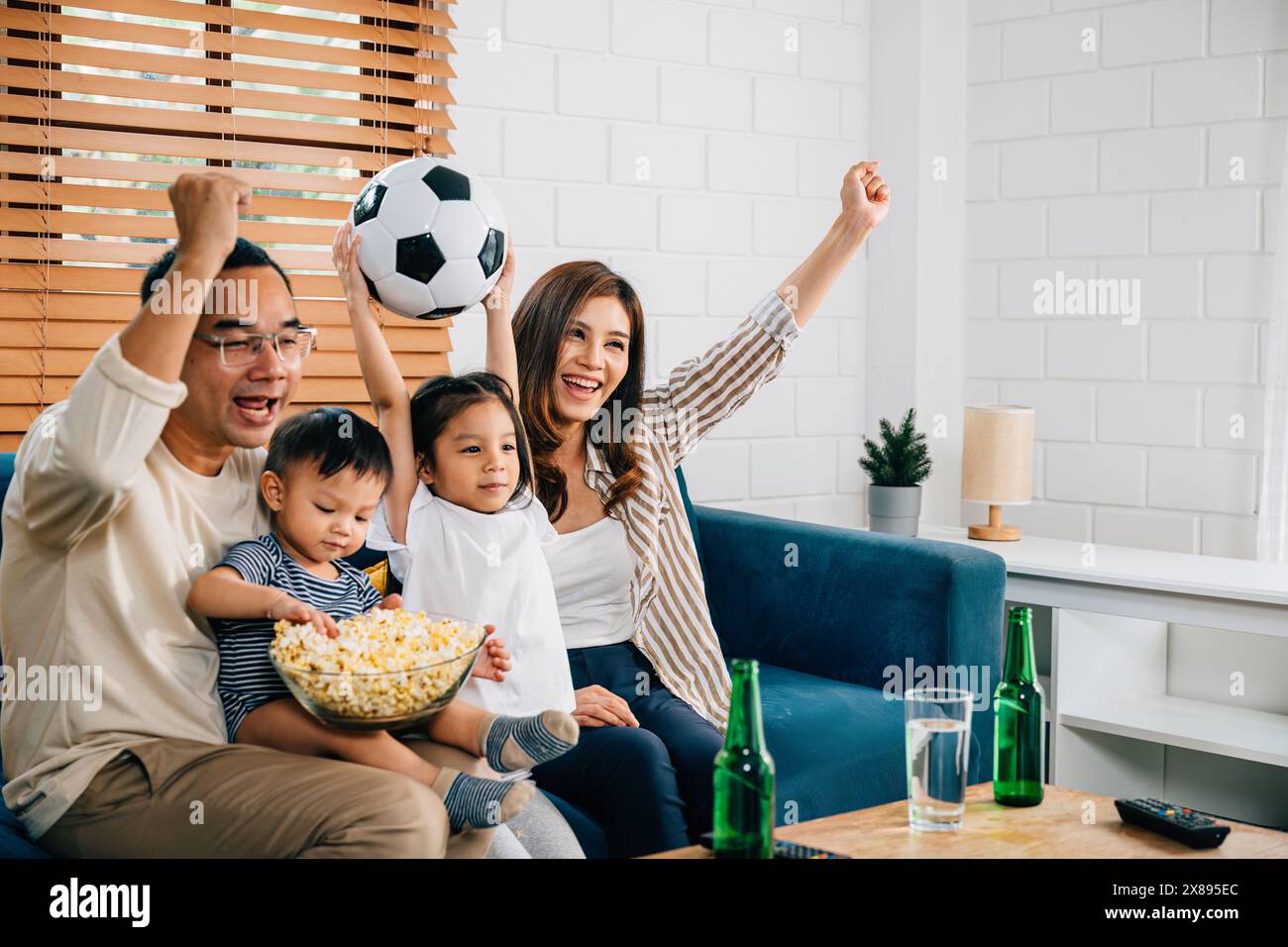 Eine glückliche Familie genießt den Nervenkitzel eines Fußballspiels zu Hause Stockfoto