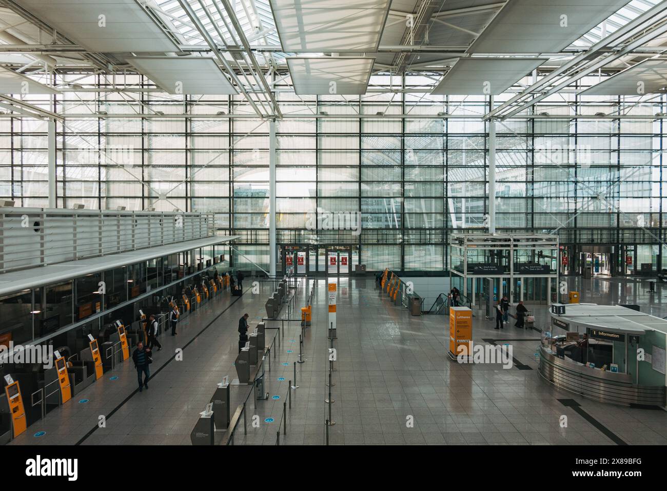 Ein leerer Check-in-Bereich im Terminal 2 am internationalen Flughafen München an einem ruhigen Nachmittag. An den Fenstern lässt sich viel natürliches Licht hereinlassen Stockfoto