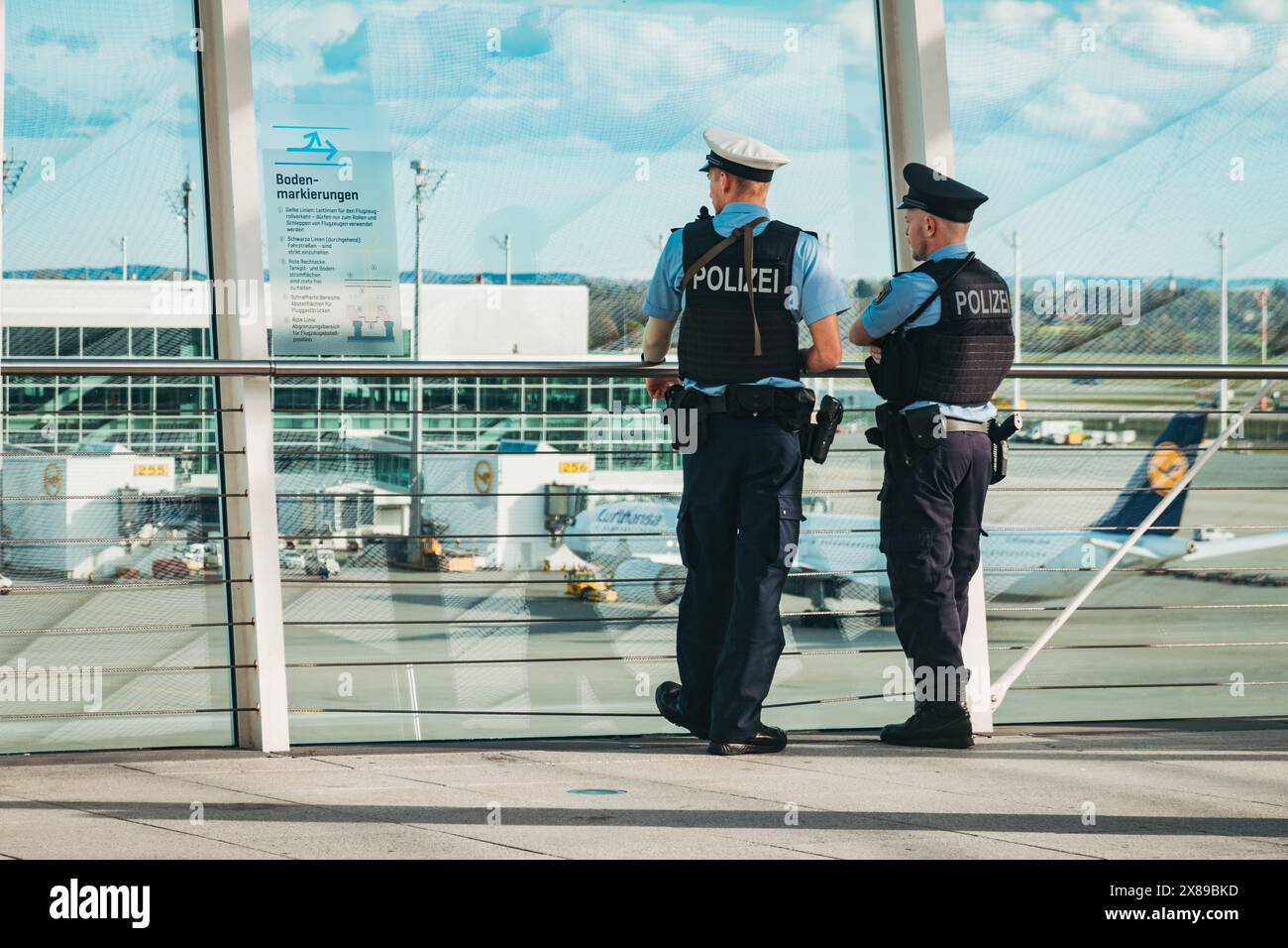 Zwei bewaffnete Flughafenpolizisten beobachten einen Rollweg am Flughafen München, Deutschland, von der Aussichtsplattform des Terminals 2 aus Stockfoto Zwei bewaffnete Flughafenpolizisten beobachten einen Rollweg am Flughafen München, Deutschland, von der Aussichtsplattform des Terminals 2 aus Stockfoto