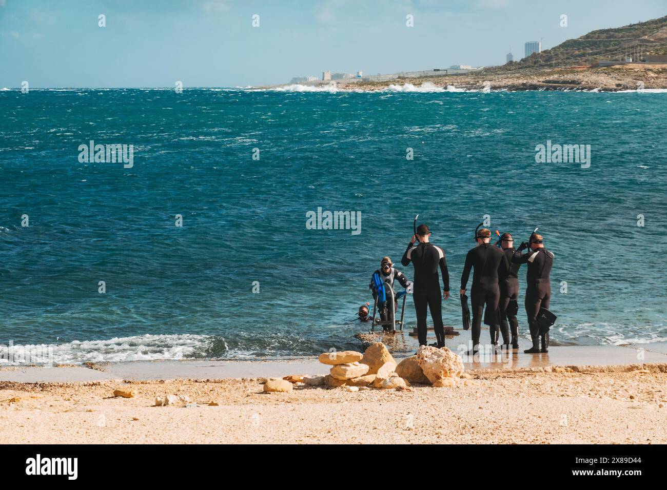 Taucher, die über eine Leiter am Qawra Point Beach, St. Paul's Bay, Malta, ins Meer absteigen Stockfoto