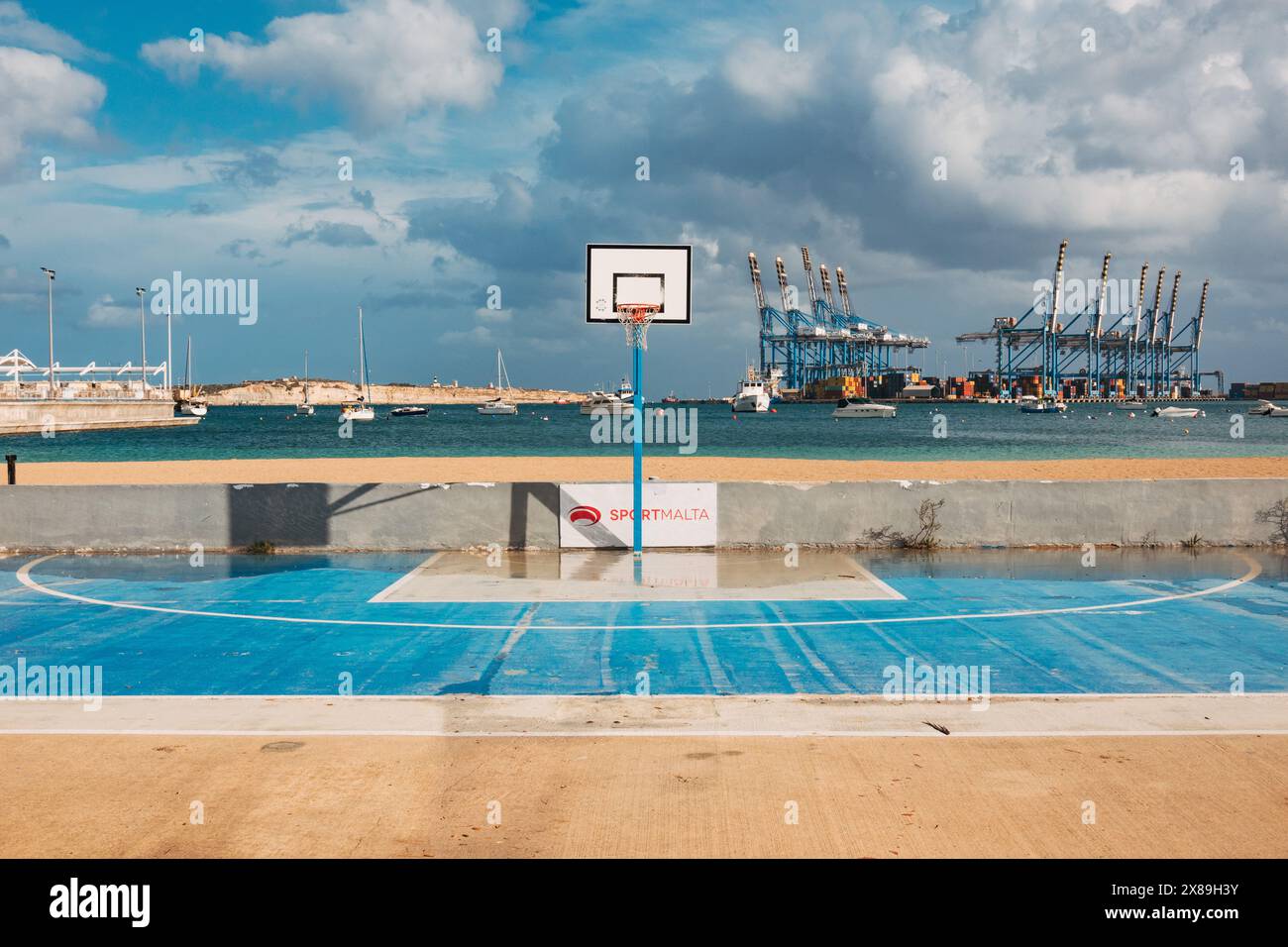 Ein feuchtes, leeres Basketballfeld, nachdem Regenwolken über Birżebbuġa, Malta, vorbeizogen Stockfoto