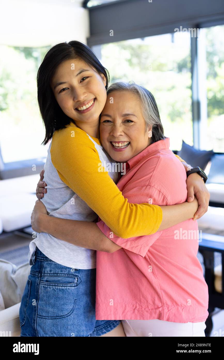Zu Hause umarmen asiatische Mutter mittleren Alters und junge Erwachsene Tochter Stockfoto