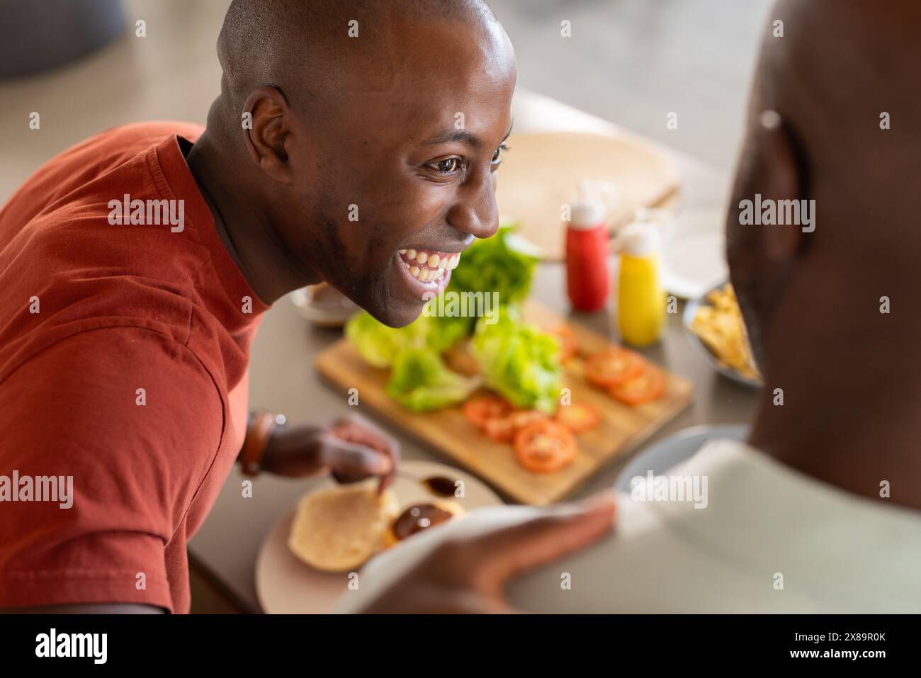 Afroamerikaner Vater und Sohn in roten Hemden bereiten zu Hause Essen zu Stockfoto