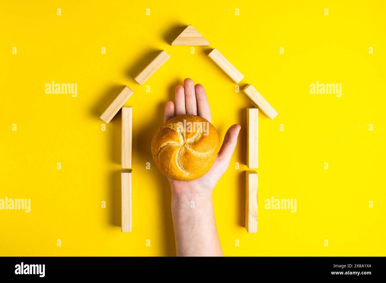 Hand hält Geldmünzen in der Nähe von Brot auf gelbem Hintergrund Stockfoto