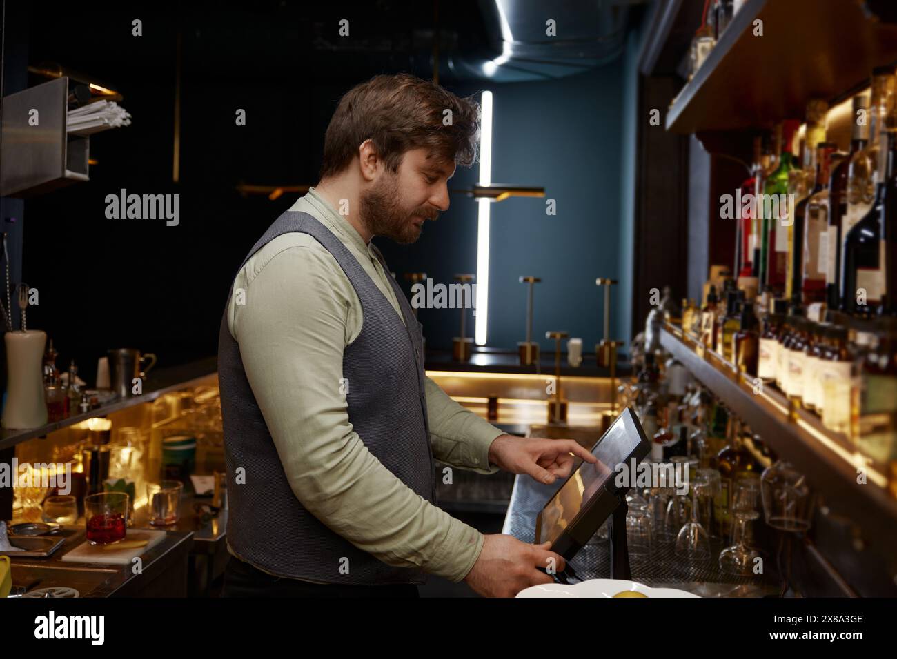 Barkeeper mit digitalem Bedienfeld zur Verarbeitung von Bestellungen für Barbesucher Stockfoto