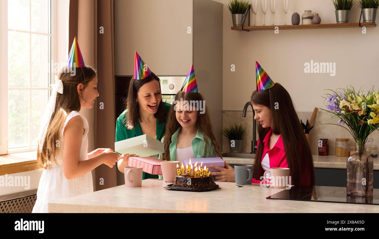 Die Familie versammelte sich, als ein Mädchen lächelnd und aufgeregt ihre Geburtstagsgeschenke öffnet. Essenz und Emotionen der Geburtstagsfeier, Atmosphäre der Freude A Stockfoto