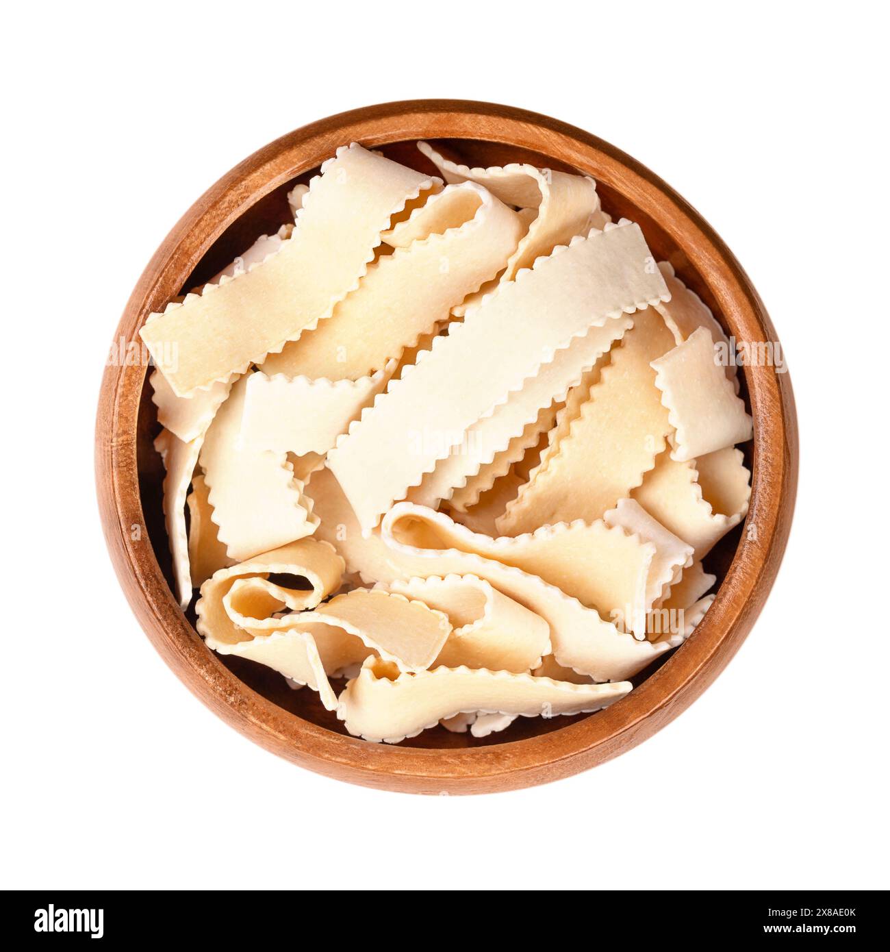 Rustiche Ribbon Nudeln mit gezackten Kanten, in einer Holzschale. Ungekochte, kurze, dicke, gezackte Nudelbänke, auch laminierte Nudeln genannt. Stockfoto