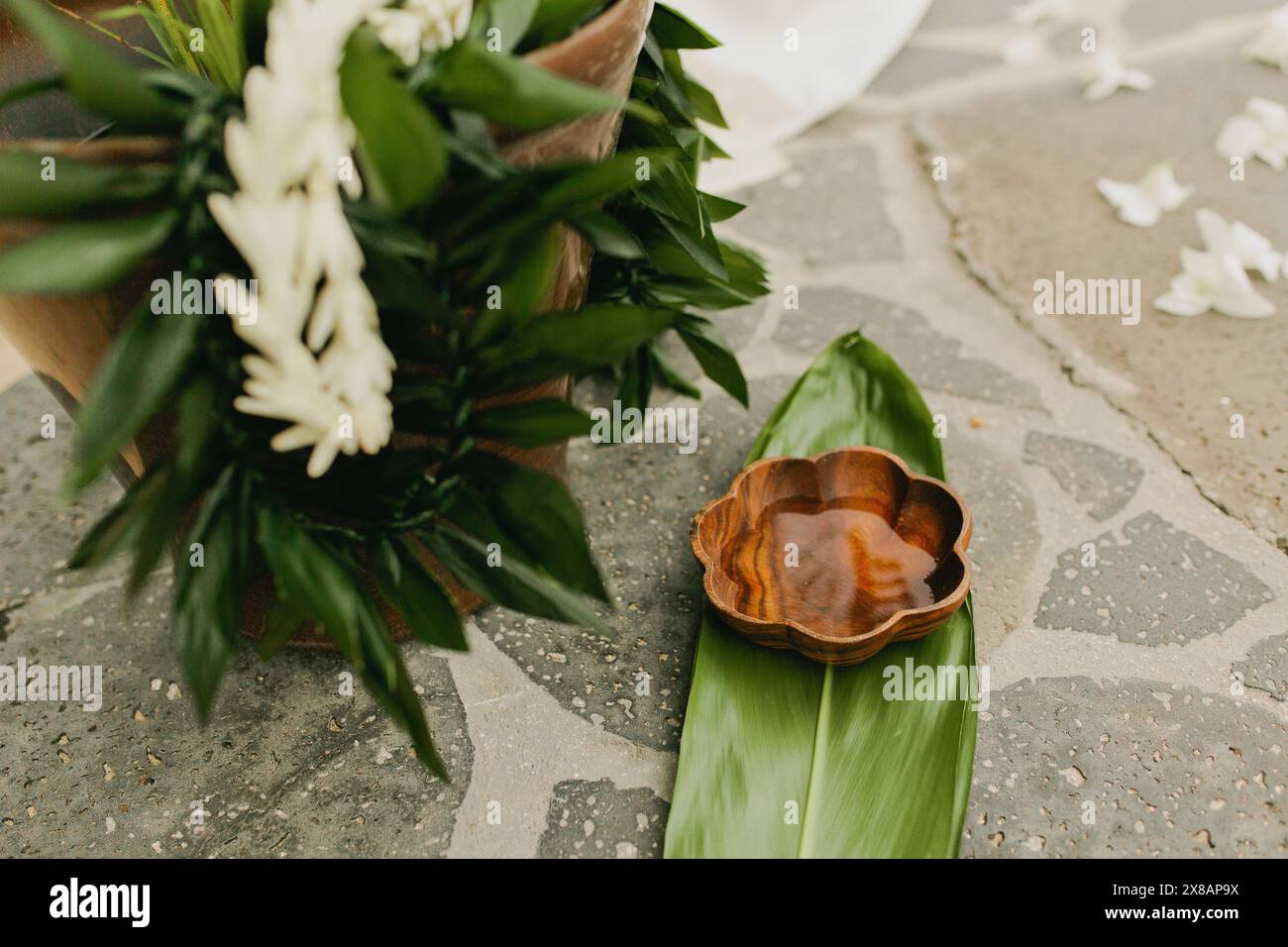 Tropische LEIs und hölzerne Wasserschale auf Grün vor der Hochzeit Stockfoto