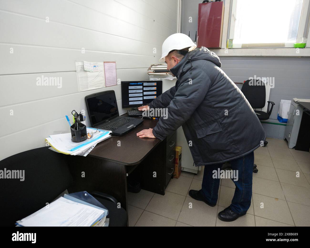 Man-Ingenieur überprüft mittels Computer den Dampfdruck in Dampferzeugungsbehältern, Operationsraum des Kesselhauses. November 2017. Slavutich, Ukraine Stockfoto