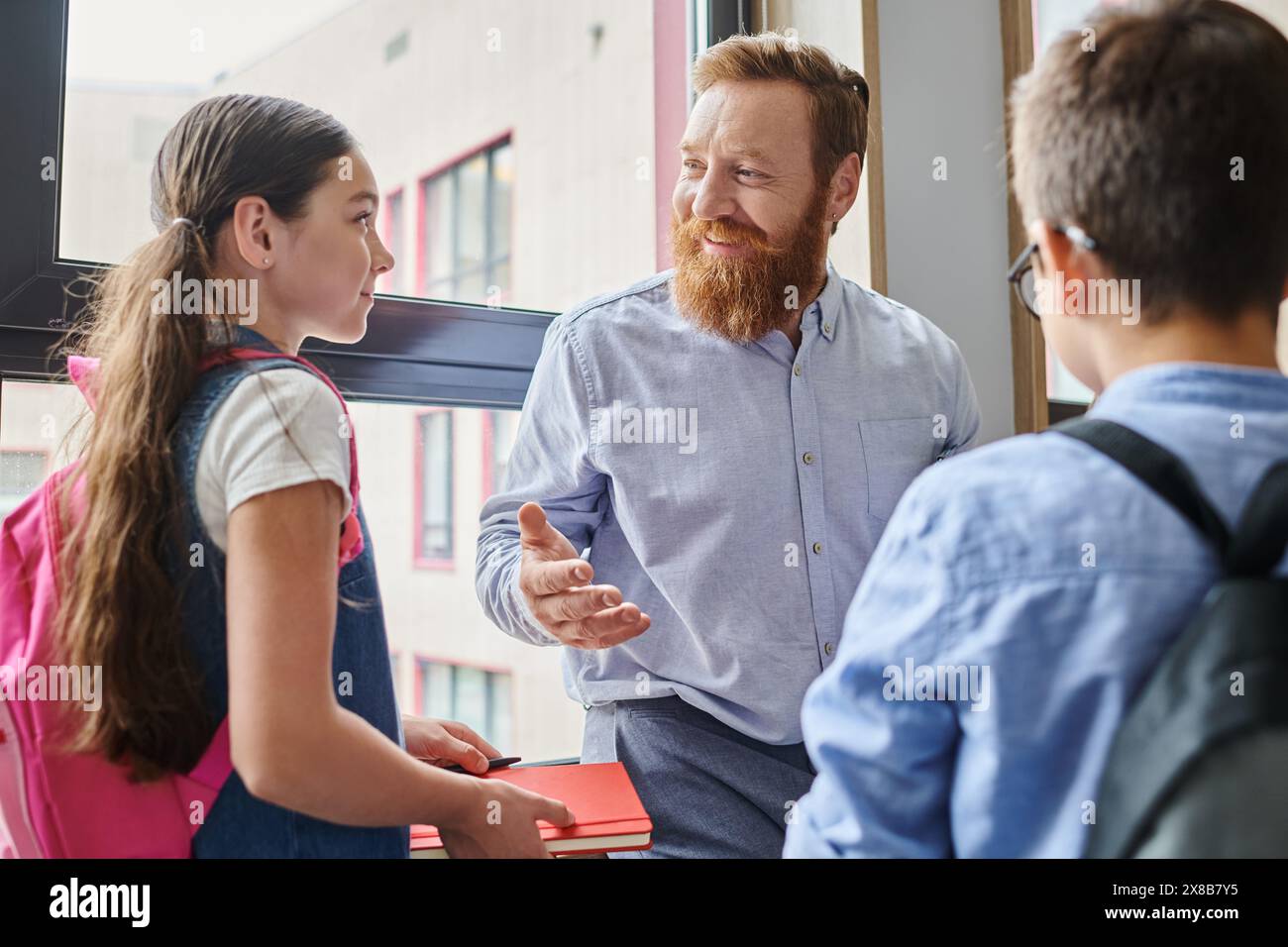 Ein bärtiger Mann unterrichtet eine vielfältige Gruppe von Menschen in einem hellen, lebendigen Klassenzimmer. Stockfoto