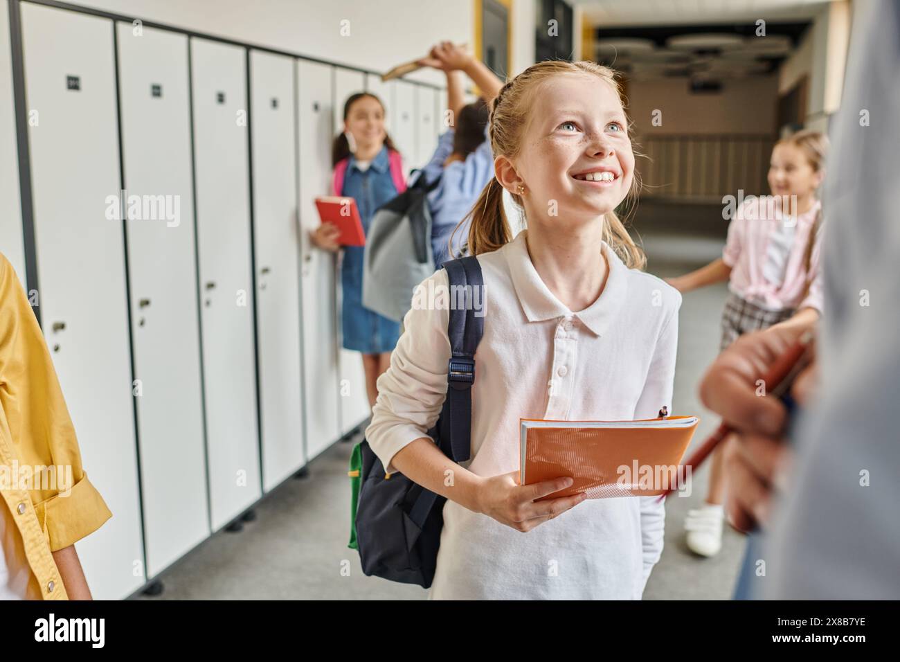 Eine Gruppe von Kindern mit unterschiedlichem Aussehen steht in einem Flur neben farbenfrohen Schließfächern. Stockfoto