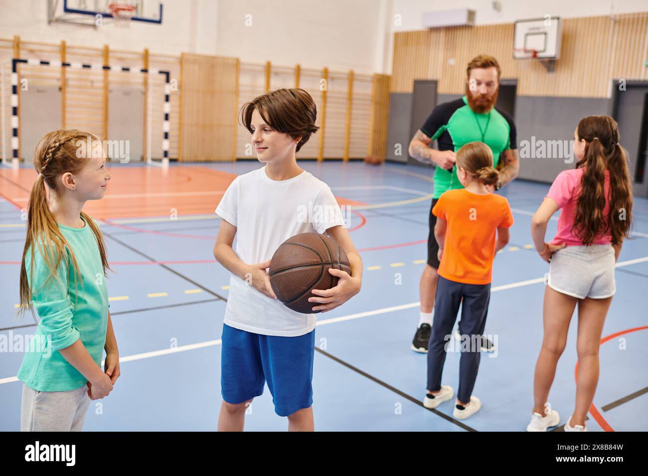 Eine vielfältige Gruppe junger Leute steht um einen Basketballplatz herum, plaudert und lacht, während ein Lehrer sie in einer lebhaften Umgebung unterrichtet. Stockfoto