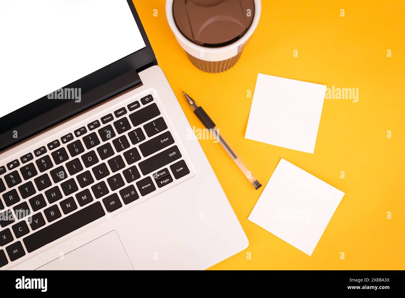 Laptop mit Platz für Text, Tasse Kaffee, Notizzettel und Stift auf gelbem Hintergrund. Draufsicht. Tastatur. Freiberuflich. Stockfoto