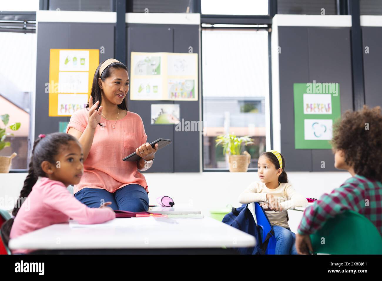 In der Schule, im Klassenzimmer, eine vielfältige Familie mit einer jungen Mutter, die ihre kleinen Kinder unterrichtet Stockfoto