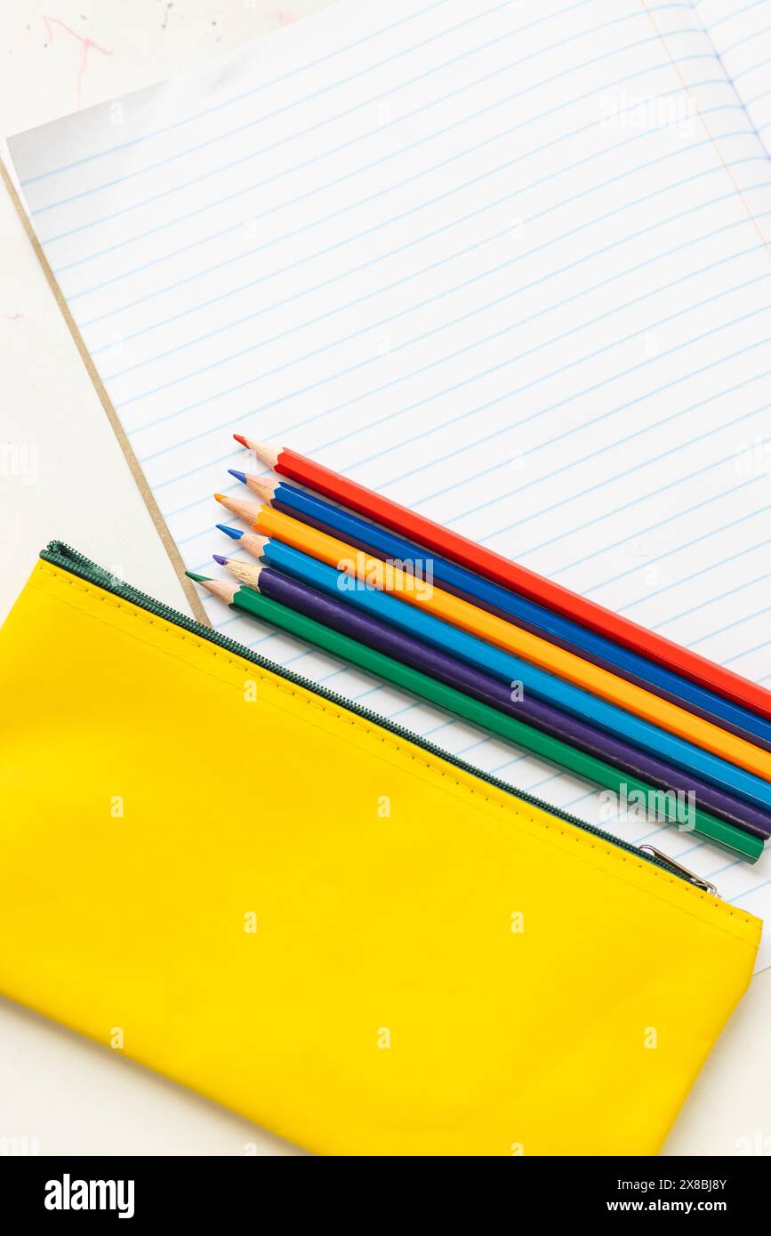 In der Schule liegen farbige Bleistifte auf einem gelben Bleistiftetui mit Kopierraum im Klassenzimmer Stockfoto