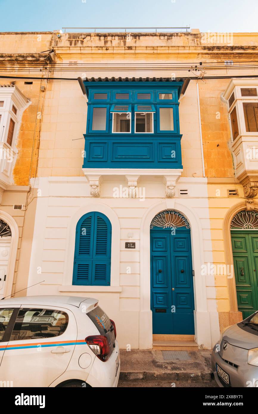 Eine Bogentür und eine Galarija (Holzbalkonfenster), die auf einem Kalksteinhaus in der Stadt Sliema, Malta, in Petrol gemalt sind Stockfoto