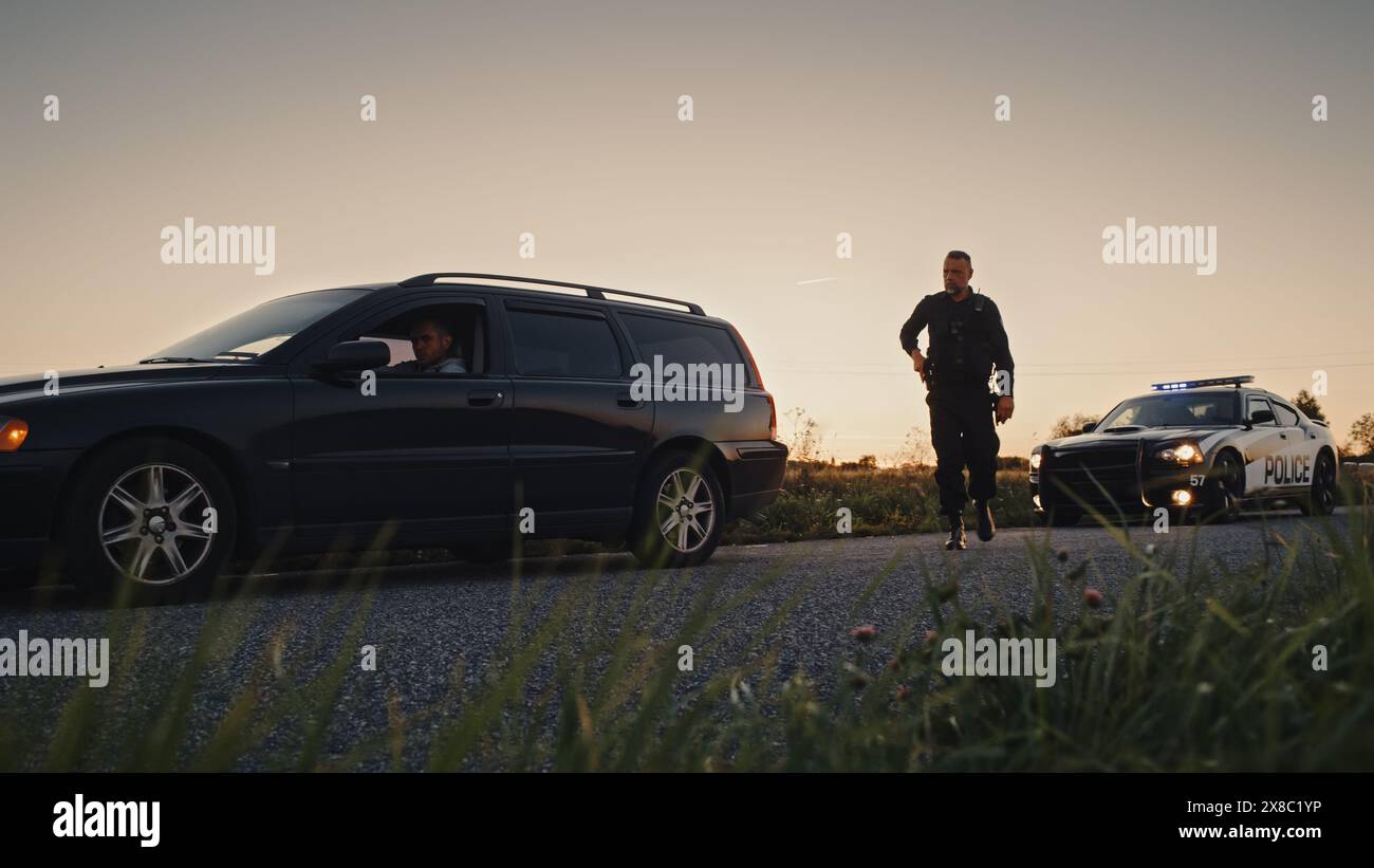 Der Rasende Fahrer Wird Von Einem Polizeiwagen Angehalten. Ein großer Schuss der beiden Autos hielt an einem Straßenübergang an und der Offizier lief auf den Verdächtigen zu. Der betrunkene Fahrer wird vom professionellen Polizisten erwischt Stockfoto