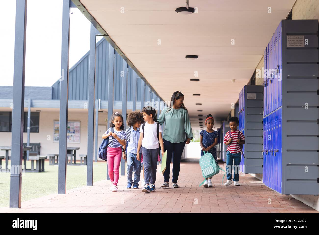 In der Schule gehen verschiedene Gruppen von Schülern mit ihrem Lehrer im Freien Stockfoto