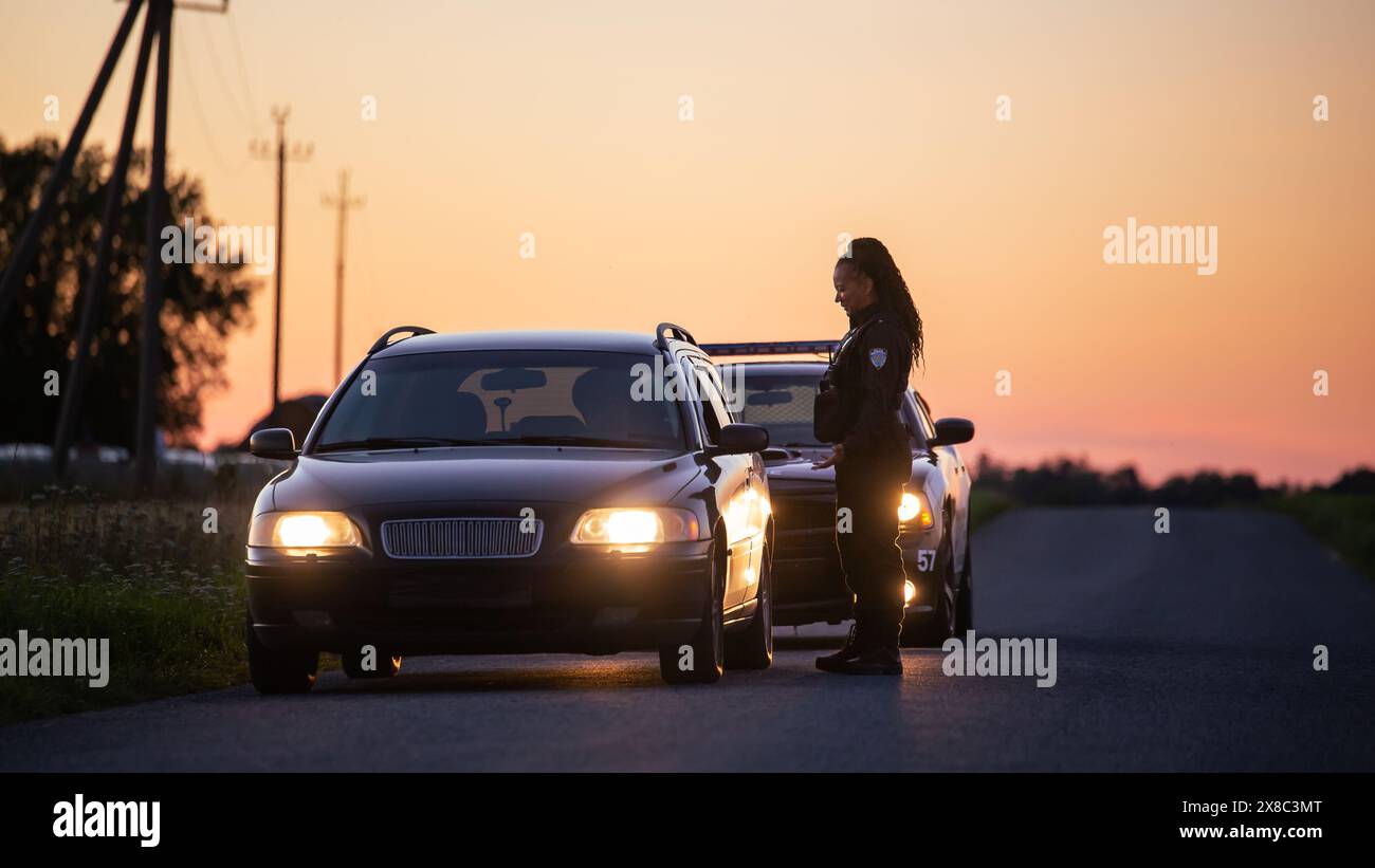Highway Traffic Patrol Auto fahren, Routine Check, Road Inspection Stop. Freundliche schwarze Polizistin lächelnd, nähert sich dem Fahrzeug, fragt nach Führerschein und Zulassung. Stockfoto